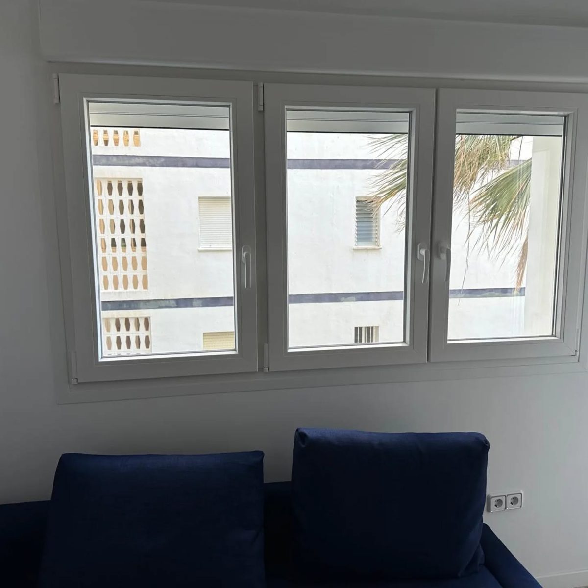 Ventana de PVC blanca de tres hojas con persiana integrada en un dormitorio